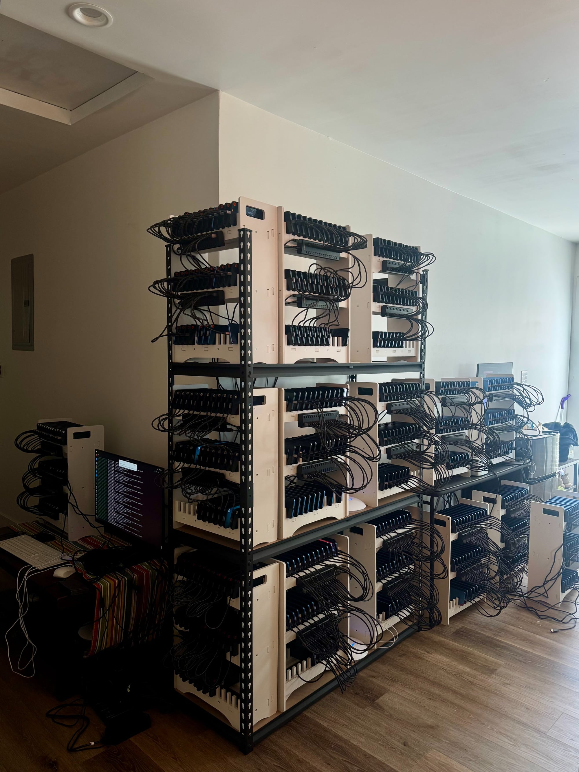 Shelves of phones on charging racks in an apartment, running doublespeed accounts